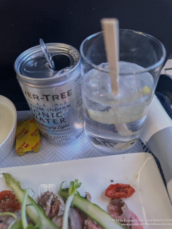 a can of water and a drink on a tray