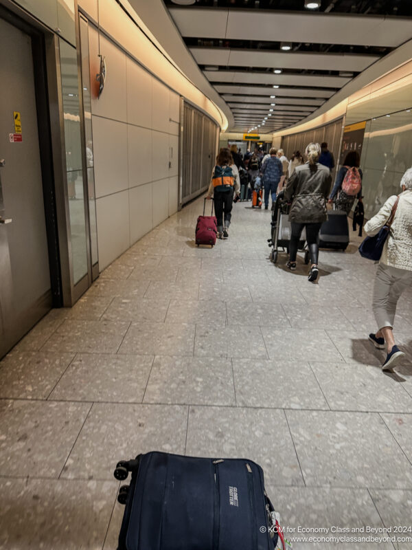 a group of people walking in a hallway with luggage