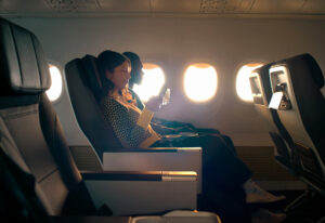 a woman sitting in a plane with a drink in her hand