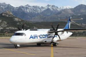 a white airplane on a runway with mountains in the background