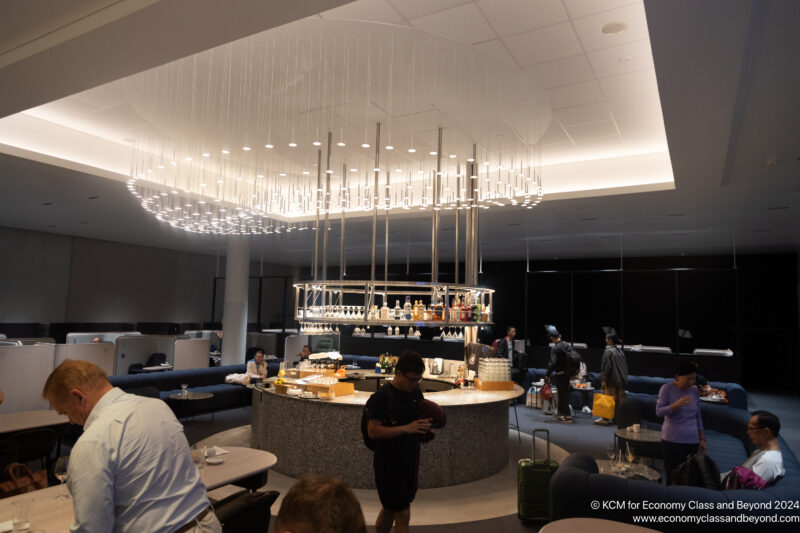 a group of people in a room with a bar and a large chandelier