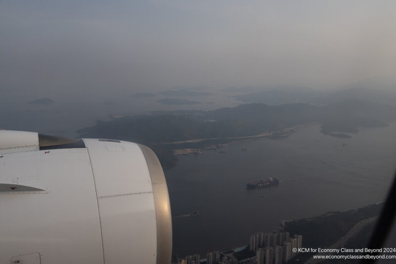 an airplane wing with a body of water and land in the background