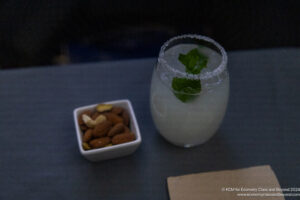 a glass of drink with a leafy rim next to a bowl of nuts