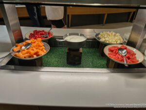 a buffet with bowls of fruit and sauces