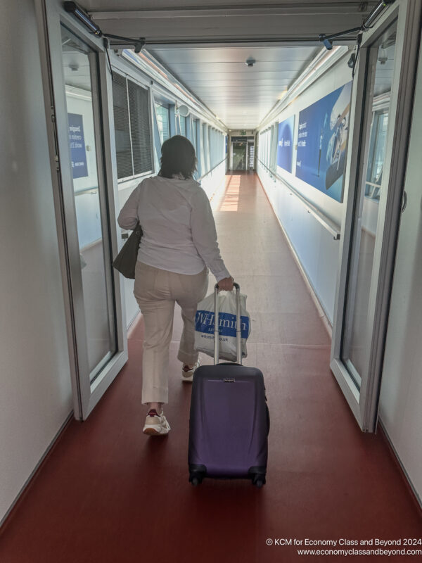 a woman walking down a hallway with luggage