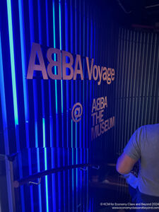 a man standing in front of a blue wall with white text