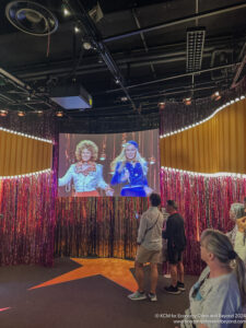 a group of people standing in front of a stage with a screen on it