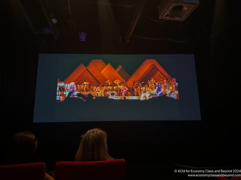 a group of people watching a performance on a projector screen