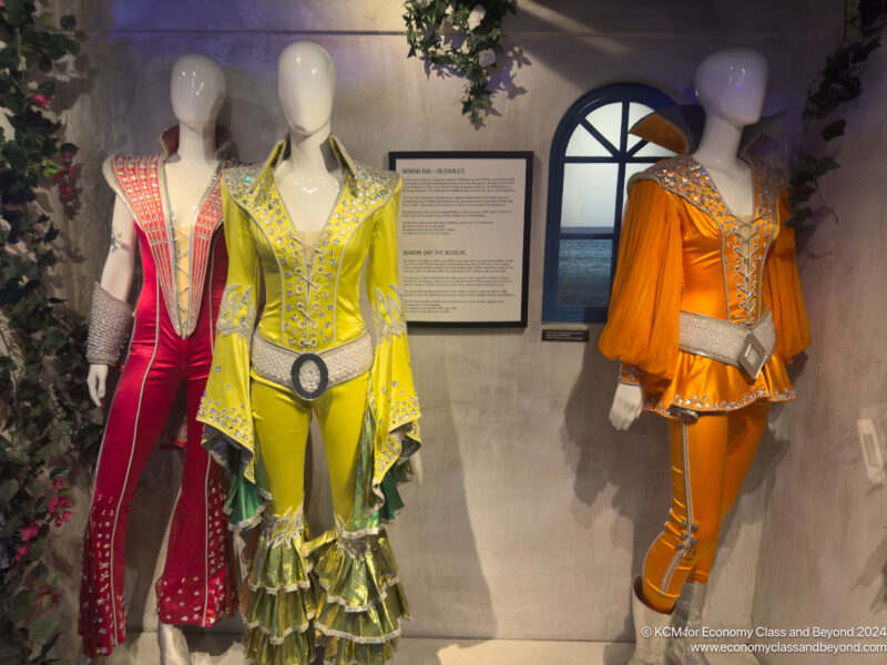 mannequins in clothing in a room with a sign and window