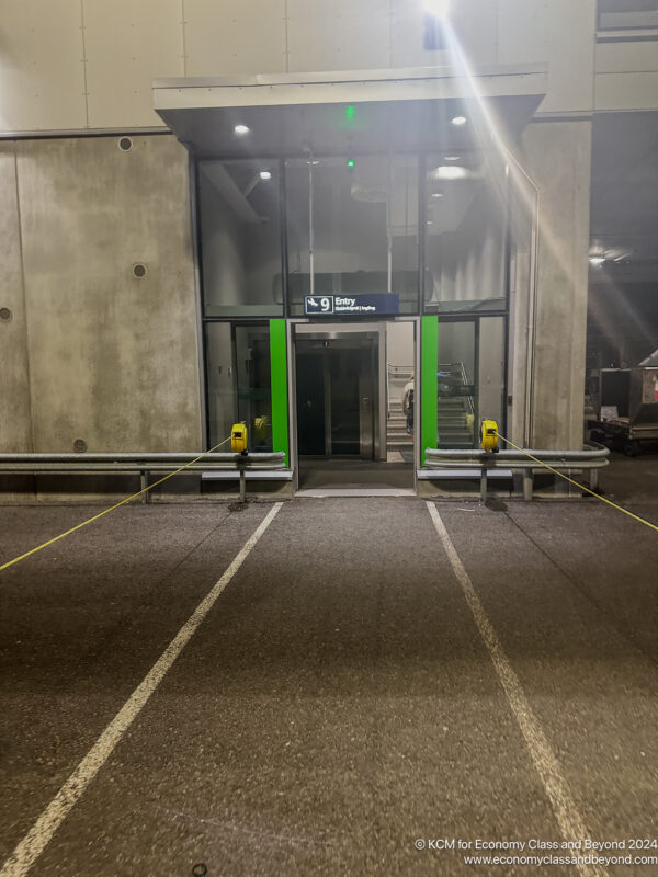 a parking lot with a green sign and yellow parking meters