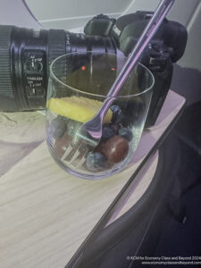 a glass with fruit and a fork on a table