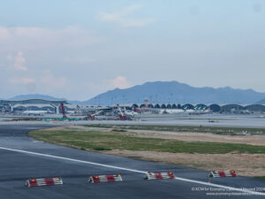 a runway with a lot of airplanes and buildings in the background