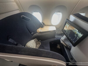 a seat in an airplane with a screen and a laptop