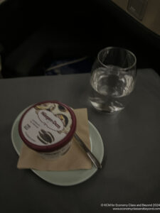 a cup of ice cream on a plate and a glass of water