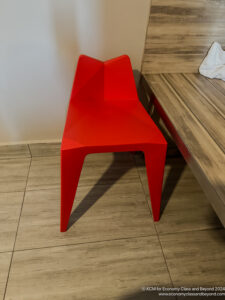 a red chair next to a wood bench
