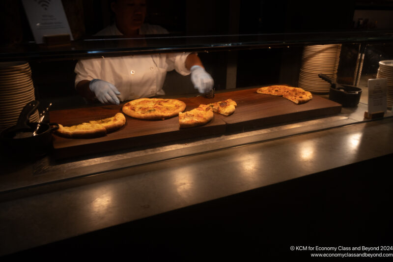 a person in gloves making pizzas