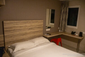 a bed with a wood headboard and a desk in a room