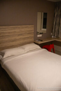 a bed with a wood headboard and a red stool