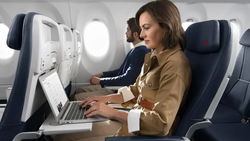 a woman and man on an airplane using a laptop