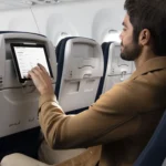 a man sitting in an airplane with a tablet