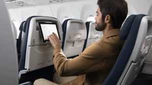 a man sitting in an airplane with a tablet