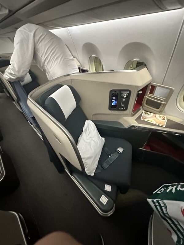 a person in a white suit standing in a chair in an airplane