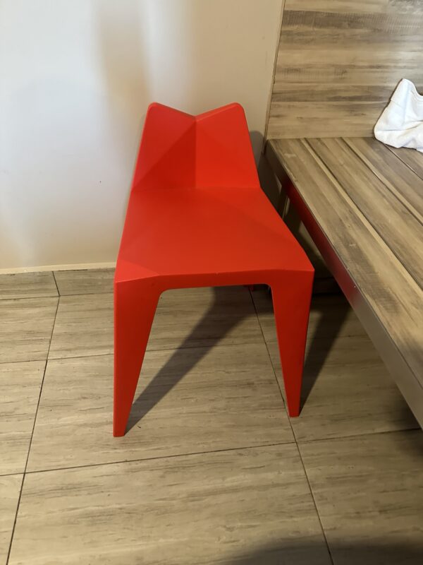 a red chair next to a wood bench