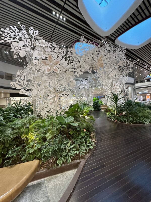 a large white tree with butterflies and plants in a mall