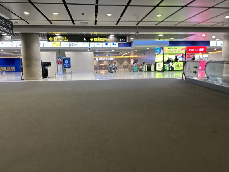 a large airport terminal with signs and people walking