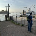 a man standing on a dock with a boat in the background