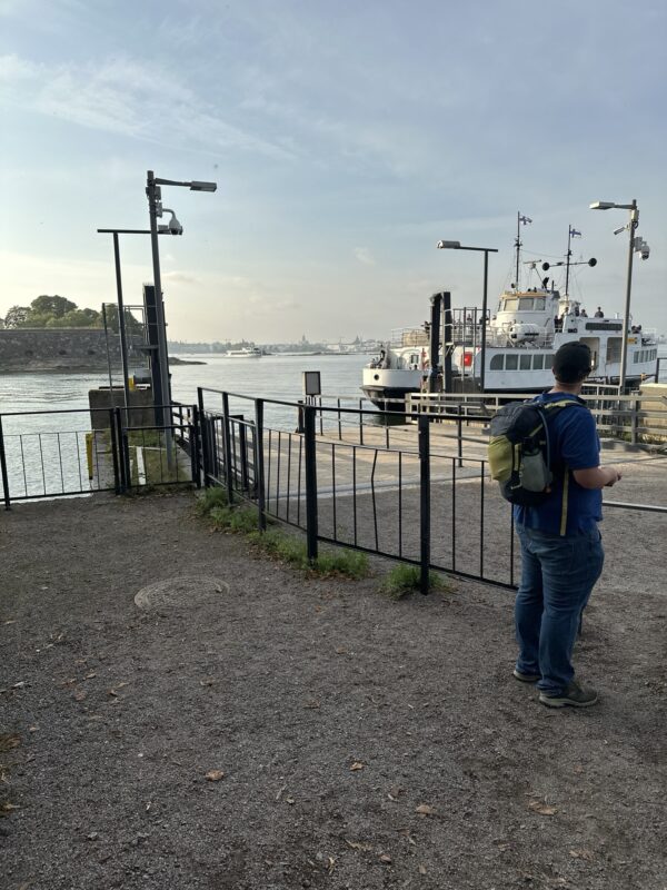 a man standing on a dock with a boat in the background