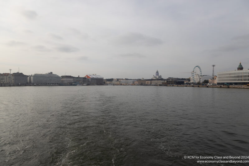 a body of water with buildings and ferris wheel