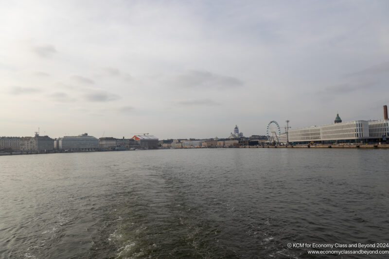 a body of water with a ferris wheel and buildings in the background