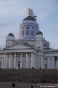 a large white building with green domes and a green roof