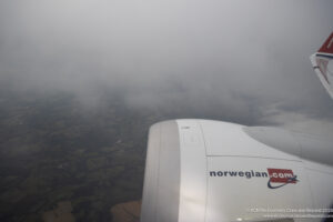 an airplane wing with clouds and land below