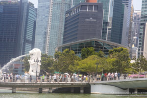 a crowd of people on a bridge over water with a statue of a lion