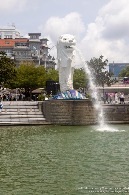 a statue of a lion with a fountain in the middle of a park