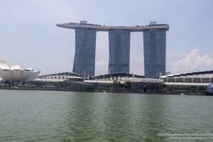 a large building next to a body of water with Marina Bay Sands in the background