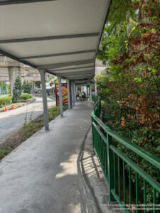 a walkway with a green railing and trees