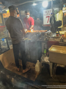 a man cooking food in a street food stall