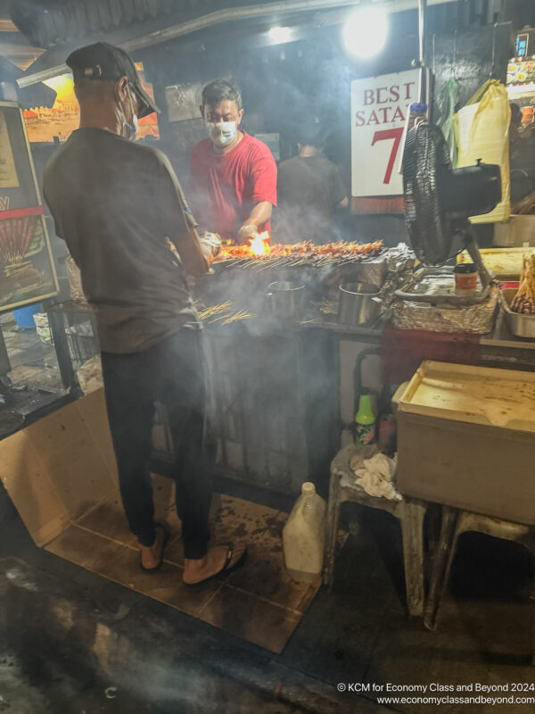 a man cooking food in a street food stall