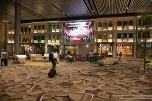 a man with luggage in a large room with many windows