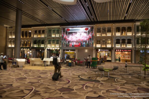 a man walking in a large room with many windows and a large screen