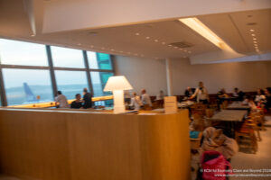 a group of people sitting at tables in a room with large windows