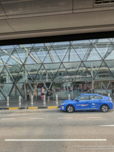 a blue car parked in front of a glass building