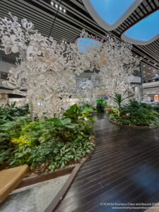 a large white tree with butterflies and plants in a mall