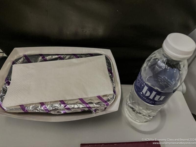 a food in a tray next to a bottle of water