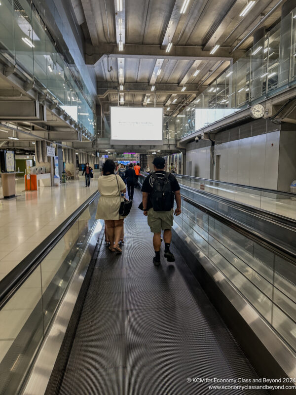 people walking on an escalator in a terminal