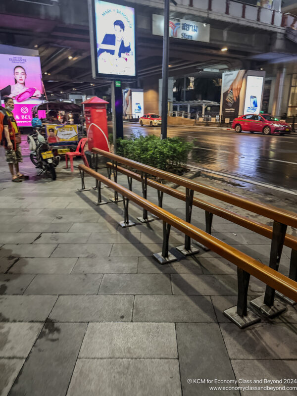 a street with a sign and a man standing next to a bench