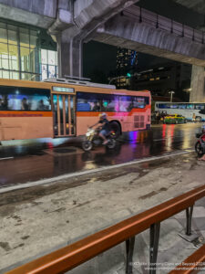 a bus and a motorcycle on a wet street